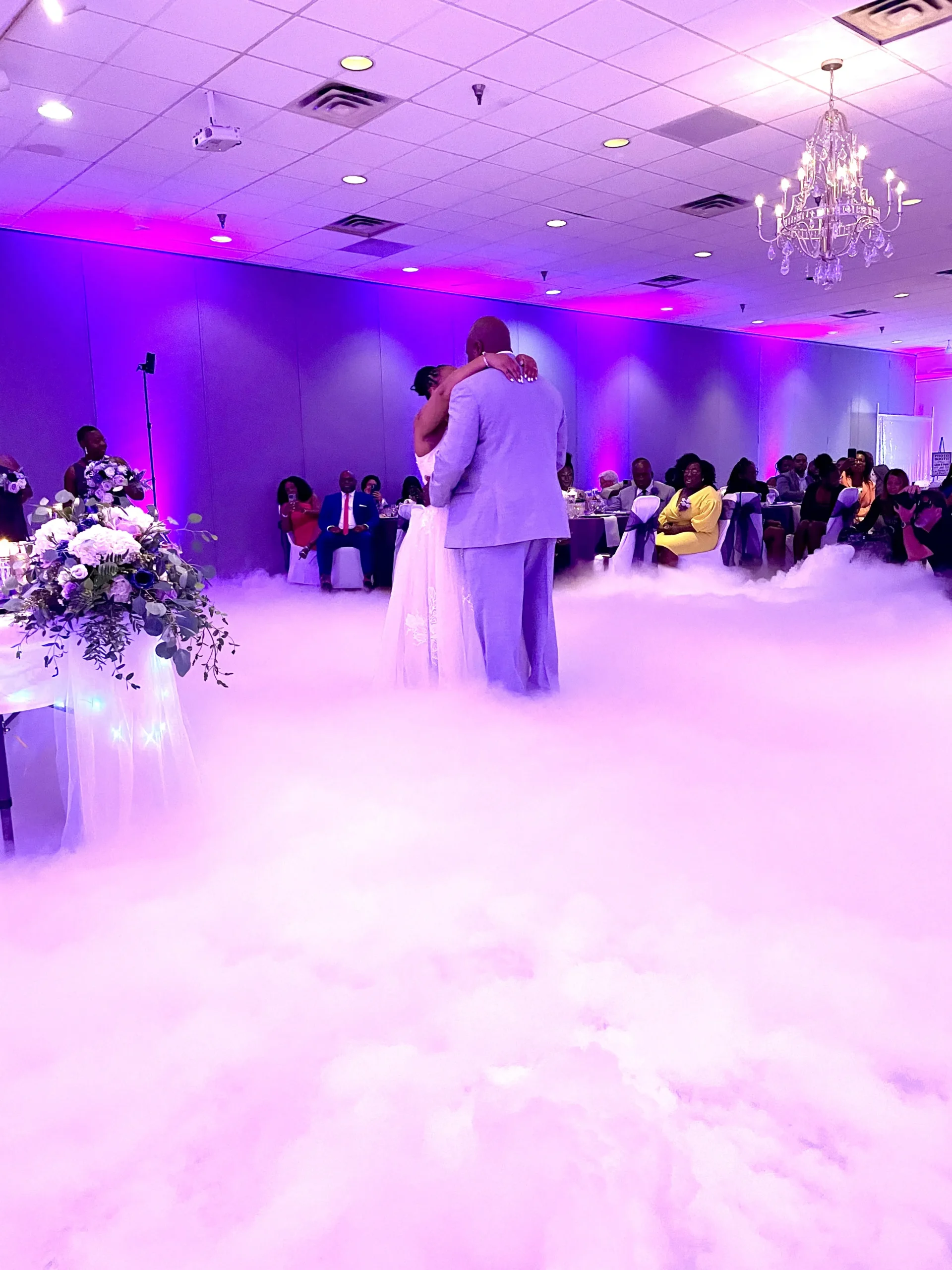Couple dancing on a low-lying fog dance floor at a wedding reception with event lighting.